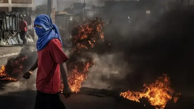Un manifestant transporte des pierres devant des barricades en feu alors que des affrontements éclatent avec les forces de sécurité malgaches lors d'une manifestation réclamant des réformes constitutionnelles à Antananarivo, le 7 octobre 2025. 