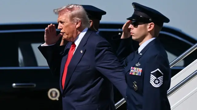 Le président américain Donald Trump salue en descendant d'Air Force One à son arrivée à l'aéroport international de Palm Beach, à West Palm Beach, en Floride, le 31 octobre 2025. 