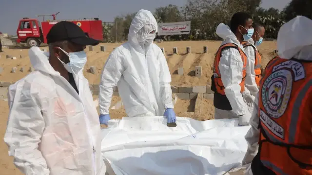 Des agents de santé et des travailleurs civils transportent les corps de Palestiniens lors d'un enterrement collectif dans un cimetière de Khan Yunis, dans le sud de la bande de Gaza, le 10 novembre 2025.