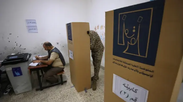 Un soldat irakien s'apprête à voter après avoir marqué son bulletin dans un bureau de vote, lors d'une journée spéciale réservée aux forces de sécurité irakiennes, deux jours avant l'ouverture des urnes au public pour les élections législatives, à Bagdad, le 9 novembre 2025.
