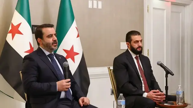 Cette photo diffusée par l'agence de presse officielle syrienne SANA le 9 novembre 2025 montre le président syrien Ahmed al-Sharaa (à droite) écoutant le ministre syrien des Affaires étrangères Asaad al-Shaibani lors d'une rencontre avec des représentants d'organisations syro-américaines à Washington DC.
