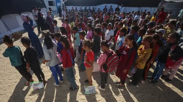 Des élèves palestiniens se rassemblent dans la cour d'une école mise en place par l'association culturelle Mayasem avec le soutien de l'UNICEF, avant le début des cours dans un camp de déplacés situé dans la région d'al-Qarara, à Khan Yunis, dans le sud de la bande de Gaza, le 7 octobre 2025.