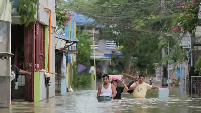 Des habitants chargés de leurs effets personnels pataugent dans une rue inondée alors qu'ils évacuent vers un endroit plus sûr dans un village de la ville de Tuguegarao, dans la province de Cagayan, au nord de Manille, le 11 novembre 2025, alors que les eaux continuent d'inonder les maisons en raison des fortes pluies provoquées par le super typhon Fung-wong.