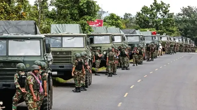 Des soldats cambodgiens debout à côté d'un convoi de lance-roquettes multiples le long d'une rue de la province de Preah Vihear.