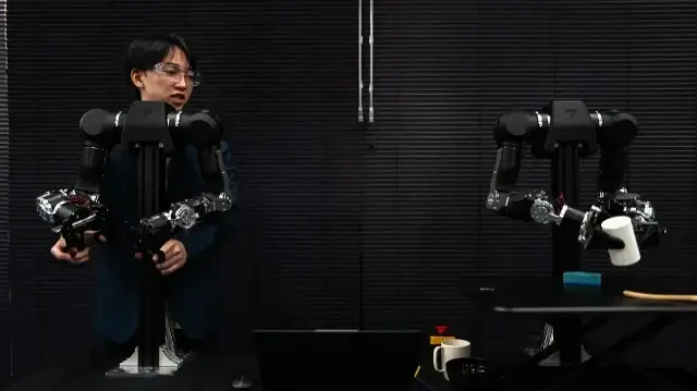 Hiro Yamamoto, PDG de la société Enactic, télécommandant un bras robotique humanoïde OpenArm depuis son bureau.