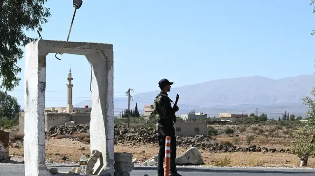 Un membre des forces de sécurité syriennes monte la garde devant une ancienne base militaire près de la ville de Quneitra, dans le sud de la Syrie, à la lisière du plateau du Golan annexé par Israël, le 21 septembre 2025.