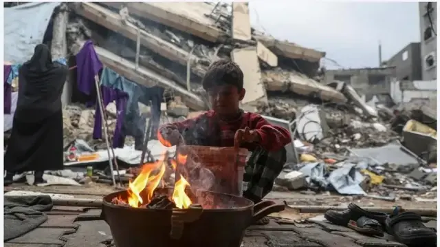 Город Газа. Палестинский мальчик пытается согреться в дождливый день во временном убежище недалеко от пляжа