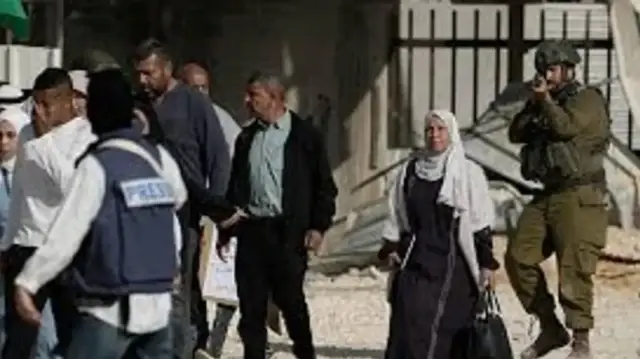 Израильский солдат направляет оружие на людей во время акции протеста с требованием вернуть перемещённых палестинцев домой, лагерь беженцев Нур-Шамс, 18 ноября 2025 г.