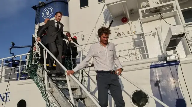 Le président français Emmanuel Macron (à gauche) et le fondateur de Plastic Odyssey Simon Bernard (à droite) débarquent du navire Plastic Odyssey à Port Louis le 20 novembre 2025. 