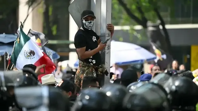 Un manifestant portant un masque représentant un crâne regarde les forces antiémeutes lors d'un rassemblement de la génération Z contre le gouvernement de la présidente mexicaine Claudia Sheinbaum, le long de l'avenue Reforma à Mexico, le 20 novembre 2025.