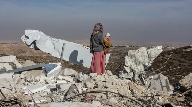 Des Palestiniens déplacés passent devant un véhicule transportant d'autres personnes à l'ouest de la ville de Deir al-Balah, dans le centre de la bande de Gaza, le 15 novembre 2025, alors qu'un système dépressionnaire touche la région.
