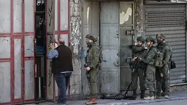 Les troupes israéliennes se préparent à entrer dans un bâtiment lors d'un raid dans la ville de Naplouse, en Palestine occupée, le 20 novembre 2025.

