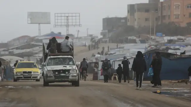 Des Palestiniens déplacés passent devant un véhicule transportant d'autres personnes à l'ouest de la ville de Deir al-Balah, dans le centre de la bande de Gaza, le 15 novembre 2025.
