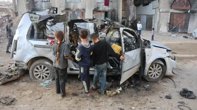Des enfants palestiniens déplacés regardent un véhicule détruit par l'armée israélienne, à Gaza, le 22 novembre 2025. 