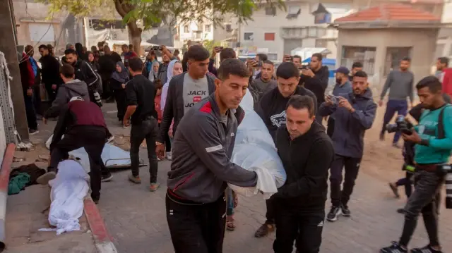 Des Palestiniens transportent les victimes d'une frappe aérienne devant l'hôpital Al-Shifa à Gaza, dans la bande de Gaza, le 20 novembre 2025.