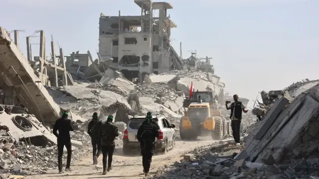 Des militants armés du Hamas palestinien accompagnés de membres du Comité international de la Croix-Rouge (CICR) suivent une pelleteuse fournie par l'Égypte, alors que les recherches des corps des otages israéliens tués se poursuivent, à Gaza, le 2 novembre 2025.