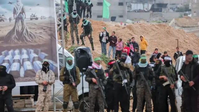 Des militants palestiniens du Hamas montent la garde alors que des personnes se rassemblent sur le site de la remise des corps de quatre otages israéliens à Khan Yunis, dans le sud de la bande de Gaza, le 20 février 2025.