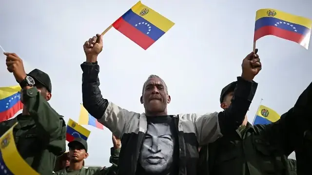 Un partisan du président vénézuélien Nicolas Maduro porte un t-shirt à l'effigie de l'ancien président vénézuélien Hugo Chavez lors d'une cérémonie militaire à Fuerte Tiuna, à Caracas, le 25 novembre 2025.