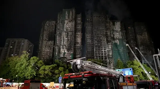 Des camions de pompiers sont stationnés à l'extérieur alors que les opérations se poursuivent après un incendie majeur qui a ravagé plusieurs immeubles d'habitation dans le quartier résidentiel de Wang Fuk Court, dans le district de Tai Po à Hong Kong, le 27 novembre 2025.