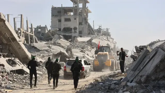 Des militants armés du Hamas accompagnés de membres du Comité international de la Croix-Rouge (CICR) suivent une pelleteuse fournie par l'Égypte, alors que les recherches des corps des otages israéliens tués se poursuivent, à Gaza, le 2 novembre 2025.