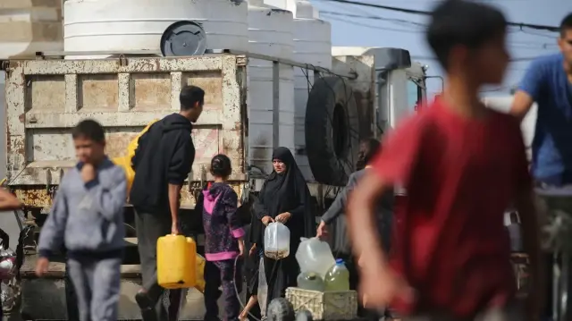 Des Palestiniens remplissent des récipients d'eau à un point de collecte dans un camp pour personnes déplacées du camp de réfugiés de Nuseirat, situé dans le centre de la bande de Gaza, le 2 novembre 2025. 
