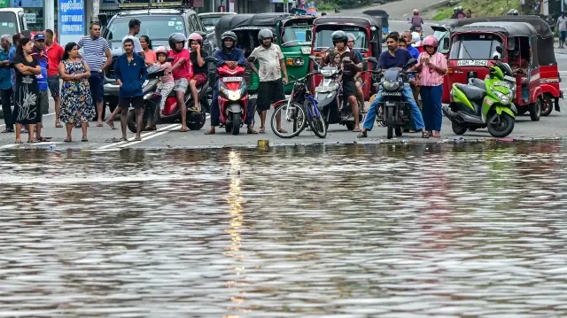 Des navetteurs se rassemblent près d'une route inondée après de fortes pluies à Kaduwela, dans la banlieue de Colombo, le 29 novembre 2025. Le Sri Lanka a lancé un appel à l'aide internationale le 29 novembre, alors que le bilan des victimes des fortes pluies et des inondations provoquées par le cyclone Ditwah s'élevait à 123 morts et 130 disparus. 

