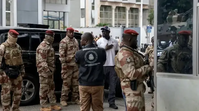 Le président guinéen Mamady Doumbouya (3e à droite) arrive dans un bureau de vote à Conakry le 21 septembre 2025, jour du référendum constitutionnel en Guinée.