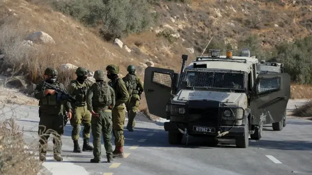 Des soldats israéliens se rassemblent près d'un véhicule blindé dans le village de Sa'ir, près de la ville cisjordanienne d'Hébron, le 23 octobre 2025.