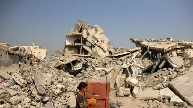 Une jeune Palestinienne porte un pot de riz qu'elle a reçu dans un refuge où vivent des familles à Gaza, en Palestine, le 5 novembre 2025.