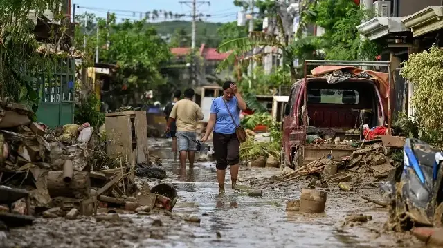 Une femme marche dans une rue recouverte de boue après le passage du typhon Kalmaegi à Liloan, dans la province de Cebu, le 6 novembre 2025.