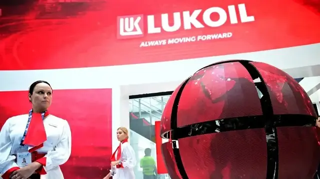 Une femme se tient à côté du logo du géant pétrolier russe Lukoil lors du Salon international du pétrole et de la conférence d'Abu Dhabi (ADIPEC) à Abu Dhabi, le 3 novembre 2025.