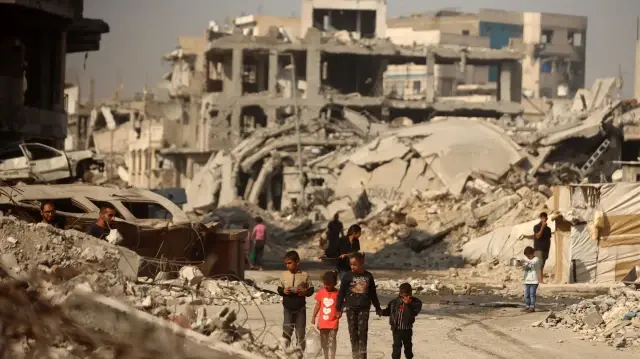 Des Palestiniens marchent parmi les décombres des bâtiments détruits dans la ville de Gaza, en Palestine, le 5 novembre 2025.