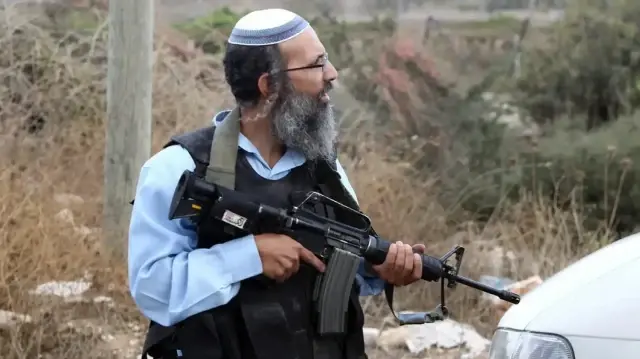 Вооруженный израильский поселенец на оккупированном Западном берегу. | Фото: WAFA