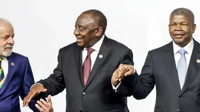 Le président brésilien Luiz Inacio Lula da Silva (à gauche), le président sud-africain Cyril Ramaphosa (au centre) et le président angolais et président de l'Union africaine Joao Lourenco (à droite) se tiennent par la main alors qu'ils posent pour une photo de famille lors du sommet des dirigeants du G20 au Nasrec Expo Centre de Johannesburg, le 22 novembre 2025. 