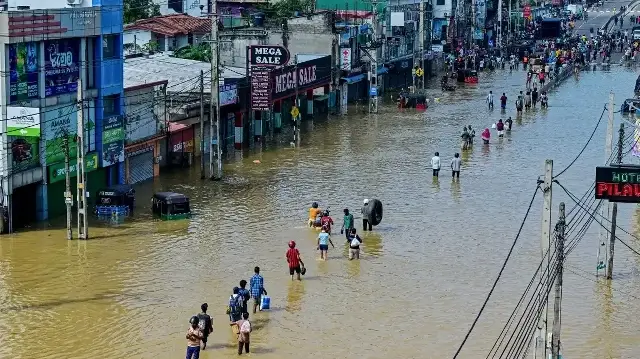 Des habitants pataugent dans une rue inondée après de fortes pluies à Wellampitiya, dans la banlieue de Colombo, le 30 novembre 2025.