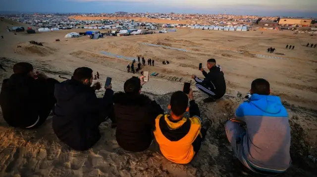 Палестинцы пытаются поймать сигнал мобильного телефона на холме напротив лагеря в Рафахе, на юге Газы. | Фото: AFP
