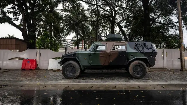Un véhicule blindé est positionné à l’entrée d’une route bloquée, à proximité de la Télévision nationale, Benin TV, à Cotonou, le 8 décembre 2025. LEs forces spéciales françaises sont intervenues en soutien pour empêcher le putsch du 7 décembre.