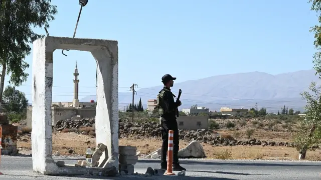 Un membre des forces de sécurité syriennes monte la garde devant une ancienne base militaire près de la ville de Quneitra, dans le sud de la Syrie, à la lisière du plateau du Golan annexé par Israël, le 21 septembre 2025.