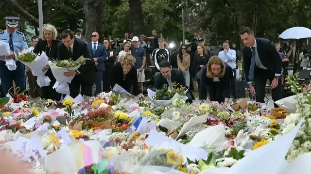 Le Premier ministre de Nouvelle-Galles du Sud, Chris Minns (à droite), et d'autres dignitaires déposent des fleurs en hommage au Bondi Pavillion, en mémoire des victimes d'une fusillade survenue à Bondi Beach, à Sydney, le 15 décembre 2025.
