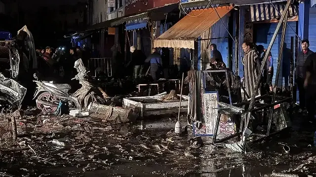 Des gens passent devant les débris laissés par une crue soudaine à Safi, le 14 décembre 2025.