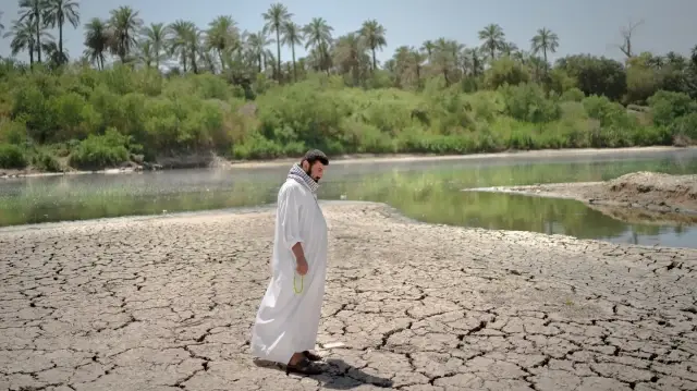 Фермер идет по высохшей земле вдоль реки Дияла - притока реки Тигр.