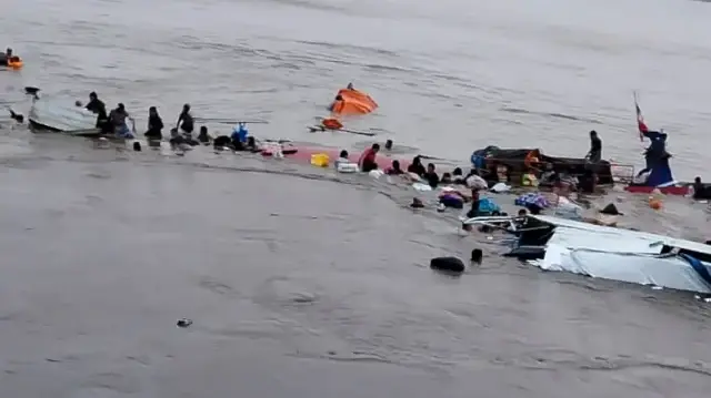 Cette photo diffusée par le COER (Centre régional des opérations d'urgence) montre des personnes autour de l'épave d'un navire impliqué dans un accident survenu dans le port d'Iparia, dans le département d'Ucayali, dans la jungle centrale du Pérou, le 1er décembre 2025.