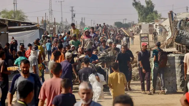 Des personnes transportent des provisions et marchent le long d'une route sablonneuse à Rafah, dans la bande de Gaza, le 28 septembre 2025.