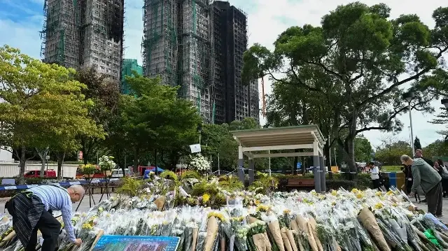 Des personnes en deuil déposent des fleurs en hommage aux victimes devant un mémorial improvisé devant les immeubles Wang Fuk Court, au lendemain de l'incendie meurtrier qui a ravagé le quartier Tai Po de Hong Kong le 26 novembre, le 1er décembre 2025.