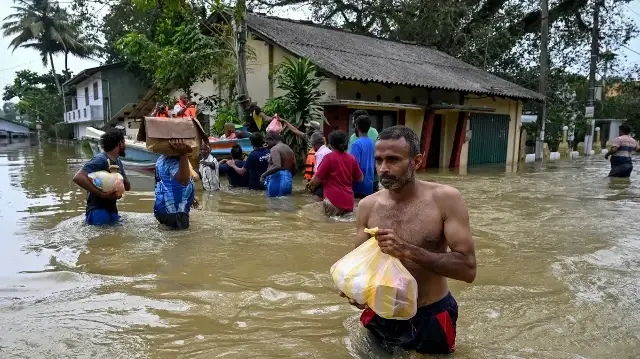Des habitants transportant leurs effets personnels traversent à gué une zone inondée après de fortes pluies à Wellampitiya, dans la banlieue de Colombo, le 1er décembre 2025.