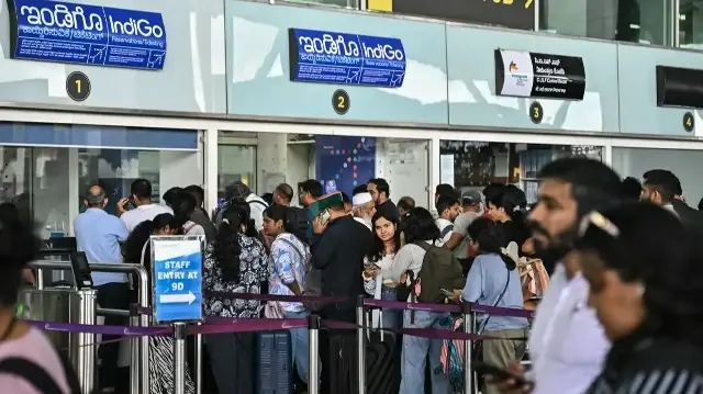 Des passagers font la queue devant un guichet Indigo Airlines à l'aéroport international Kempegowda de Bengaluru, le 4 décembre 2025.