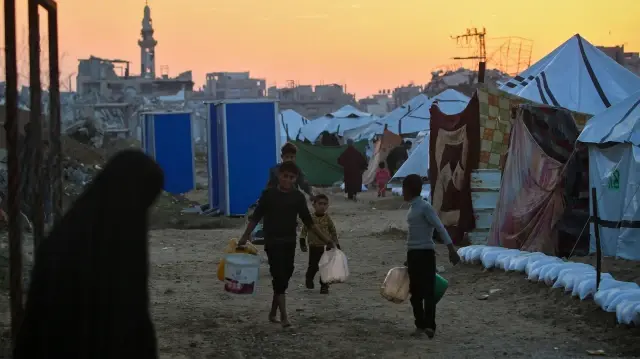 Des enfants transportent de l'eau dans le camp de Nuseirat pour Palestiniens déplacés, dans le centre de la bande de Gaza, le 4 décembre 2025.