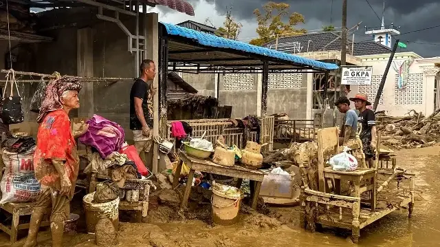 Des villageois touchés par des crues soudaines nettoient la boue de leur maison et de leurs biens dans le village d'Aek Ngadol, dans la régence de Tapanuli Sud, province de Sumatra Nord, le 5 décembre 2025.