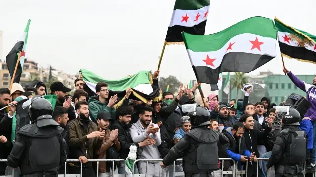 Des personnes brandissent des drapeaux syriens pour célébrer le premier anniversaire du renversement du dirigeant de longue date Bachar al-Assad à Damas, le 8 décembre 2025.