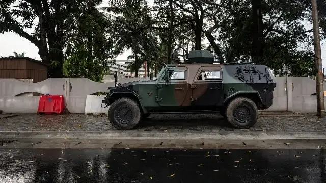 Un véhicule blindé est positionné à l'entrée d'une route bloquée à côté de la télévision nationale, Bénin TV, à Cotonou, le 8 décembre 2025.